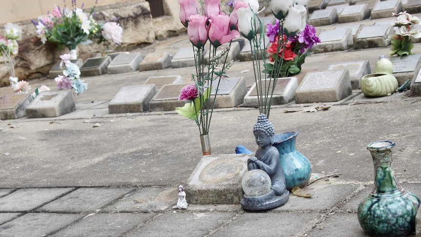 A grave stone with no name on it. There's a buddha statue, and flowers.