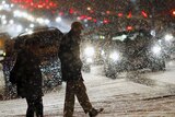 People cross a street as it snows in Washington.