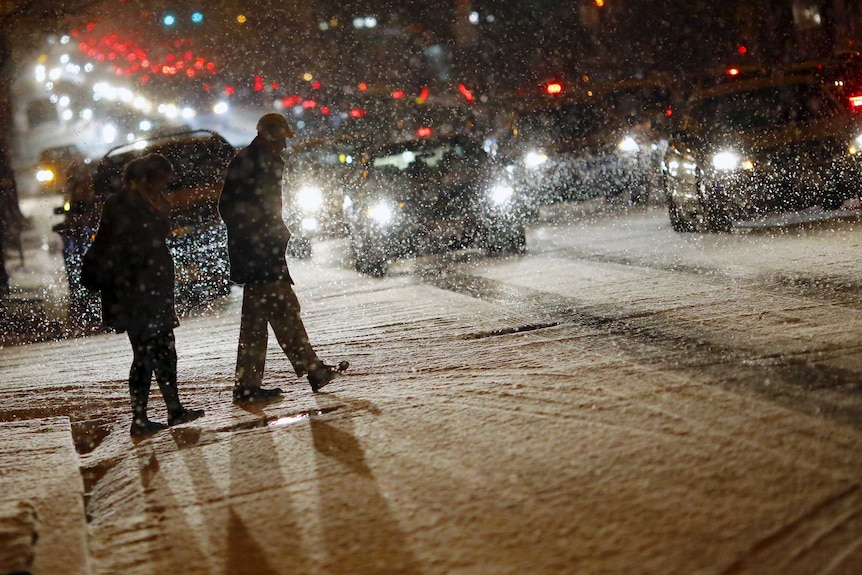 People cross a street as it snows in Washington.