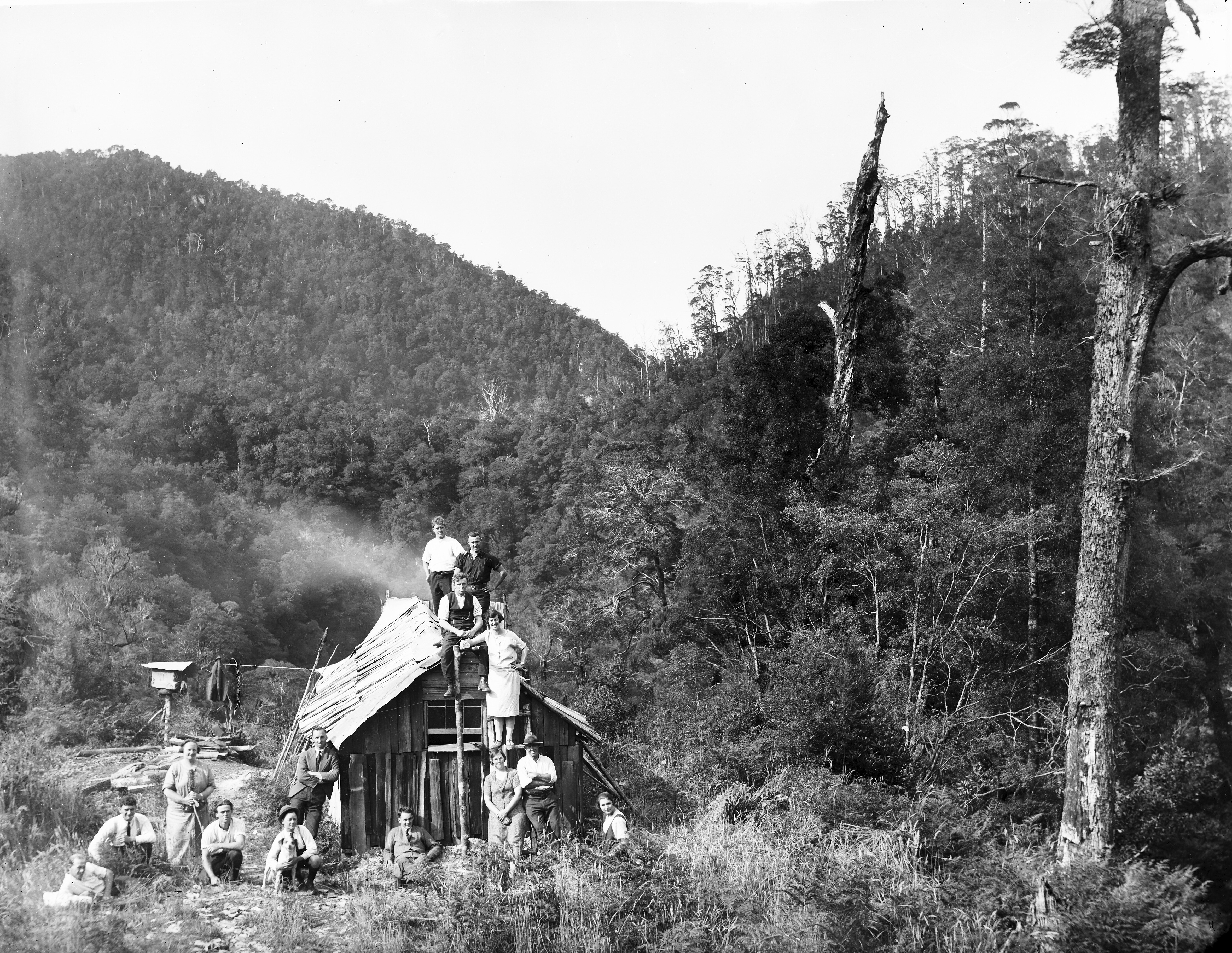 a black and white photo of people around a hut in the landscape