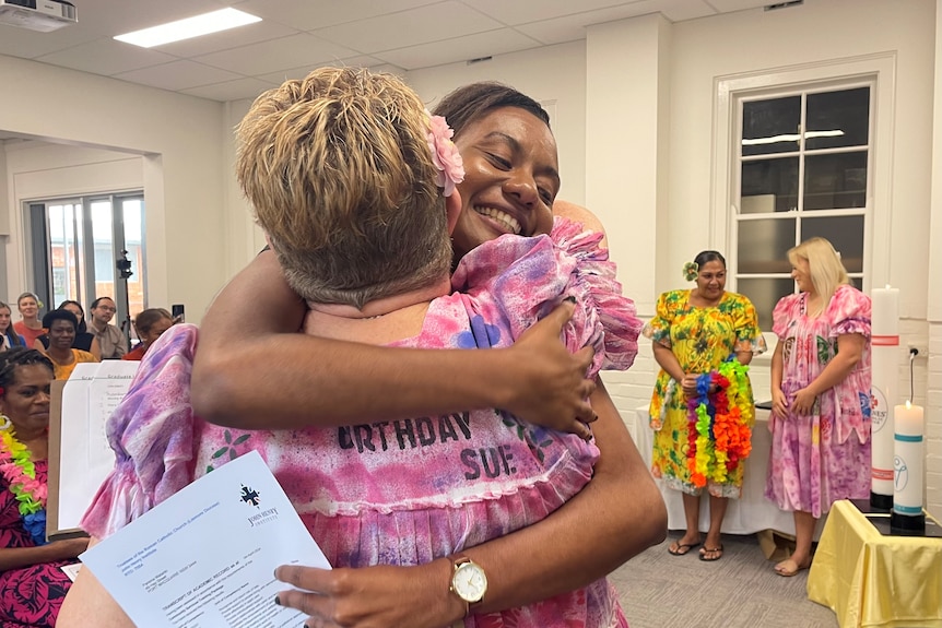 A woman with short blone hair hugs a woman from Vanuatu holding a graduation certificate.