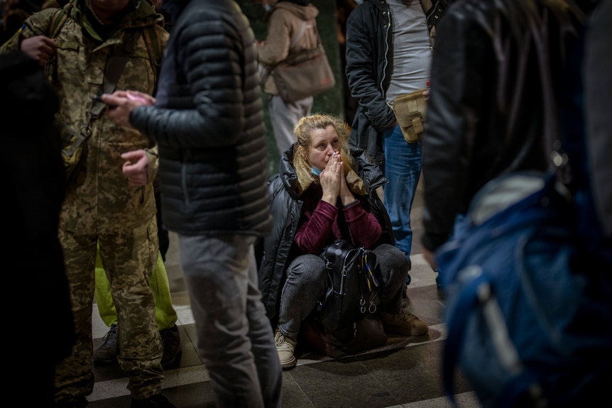 A woman reacts as she waits for a train trying to leave Kyiv.