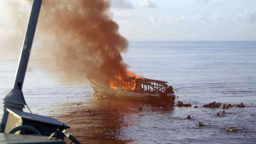 Asylum seekers struggle in the water near their exploded boat.