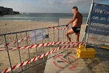 A man crossing a barrier on Bondi Beach.