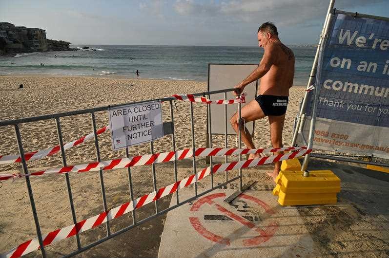 A man crossing a barrier on Bondi Beach.