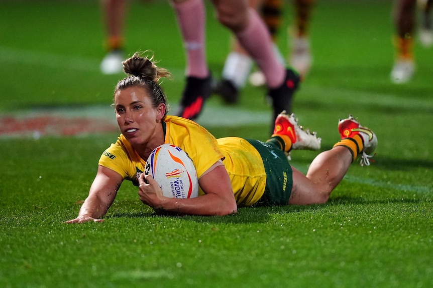 Jillaroos player Sam Bremner slides on her front to score a try in Australia's Rugby League World Cup game against Cook Islands.