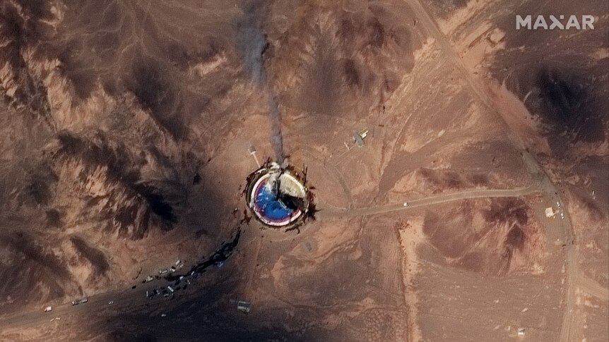 A satellite image of a circular launch site that appears to be smoking