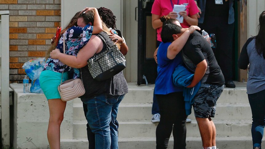 People embrace outside of the school where a shooting took place