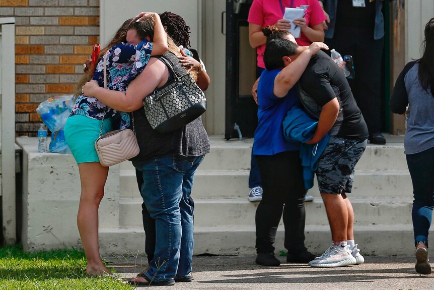 People embrace outside of the school where a shooting took place