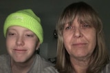 A 16-year-old boy with cancer wears a beanie with his mother