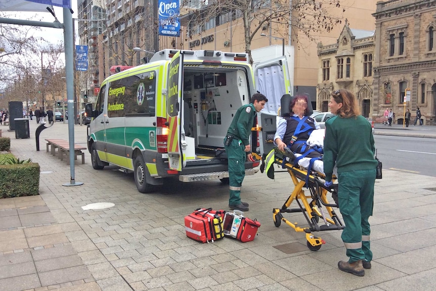 Paramedics deal with a person on a stretcher in an Adelaide CBD street.