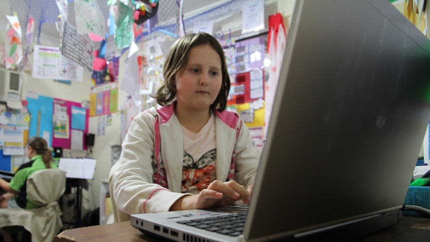 A girl doing her homework on a computer in her room