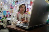 A girl doing her homework on a computer in her room