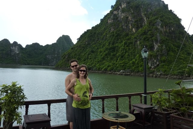 A man and woman cradle the woman's pregnant belly against the backdrop of Vietnam's Halong Bay