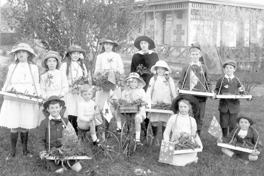 An old black and white photo of children holding trays of flowers