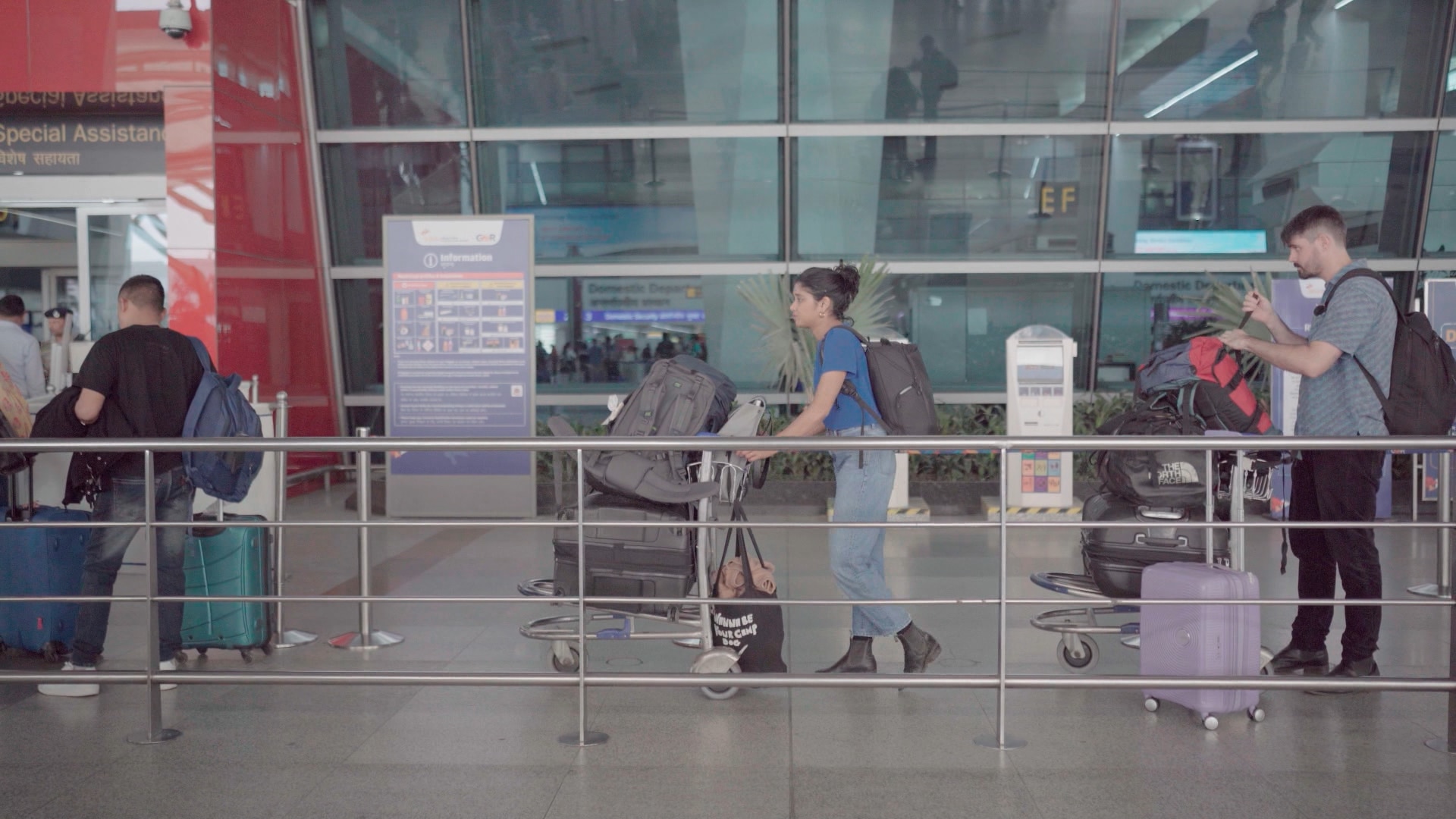 A woman stands in a queue with a trolley of suitcases.