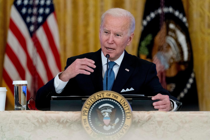 Joe Biden speaks at a podium during a meeting