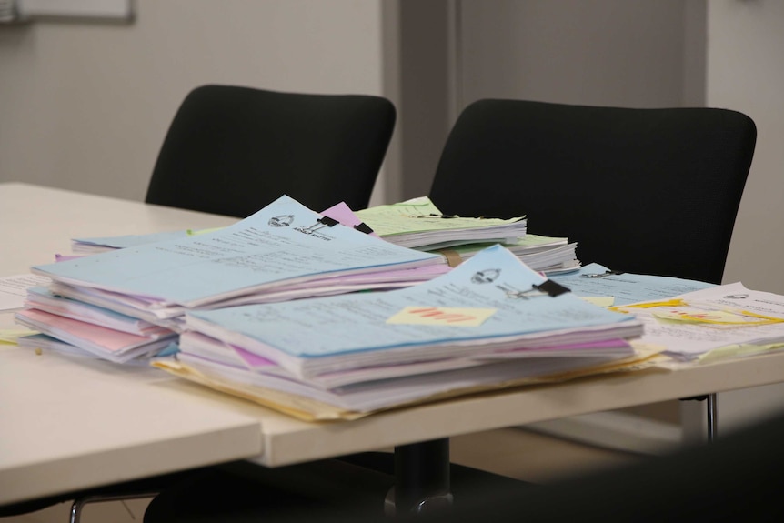 Case files are stacked on a table inside bush court in Wadeye