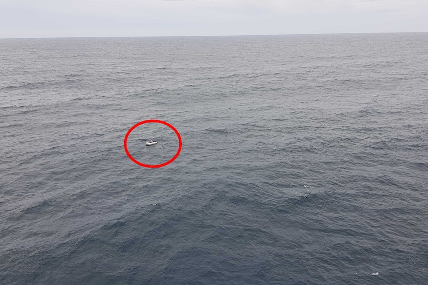 An aerial image showing a small inflatable dinghy on a vast expanse of water.