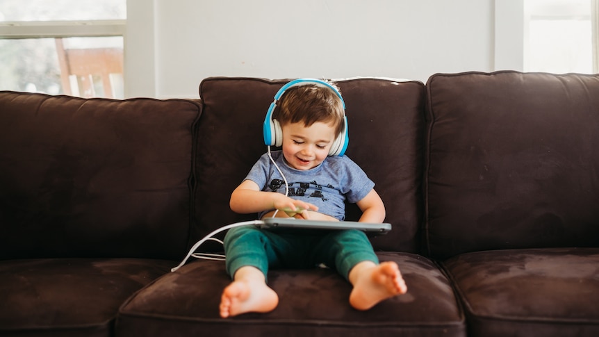 Small child smiling with headphones and tablet