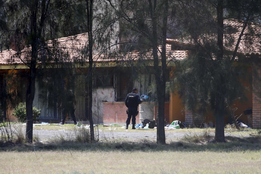 Police officers stand guard inside a ranch where a firefight took place