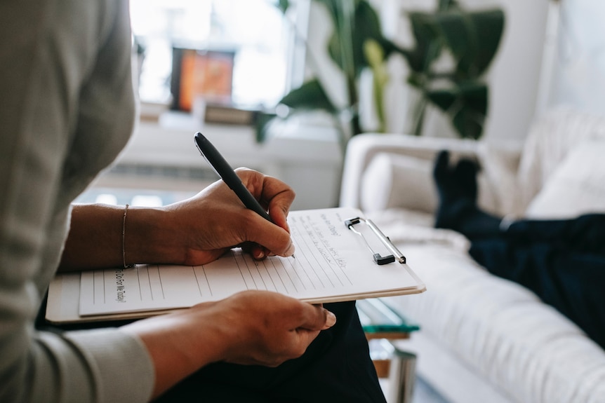 Psychologist's hands taking notes on a notepad