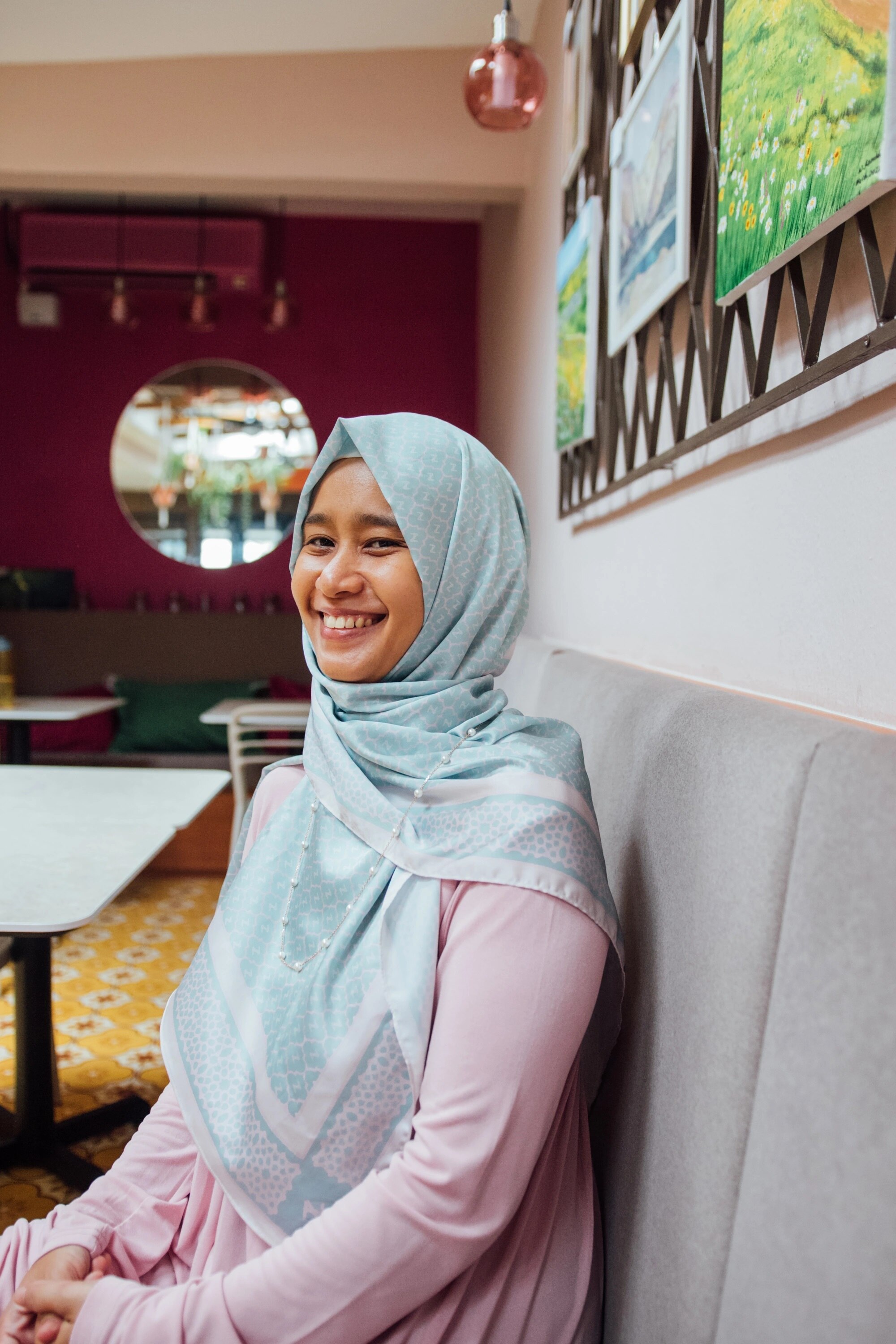 A photo of Raidah smiling, wearing pale blue hijab.