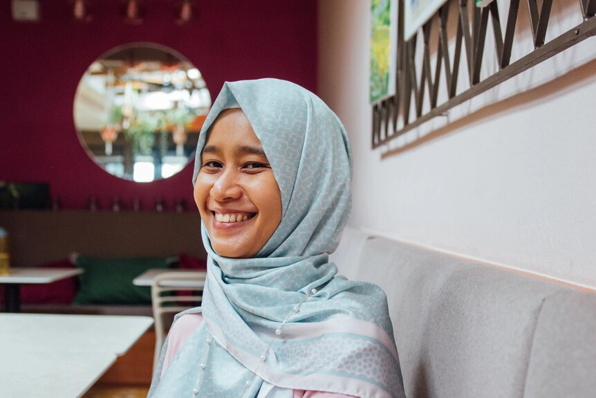 A photo of Raidah smiling, wearing pale blue hijab.