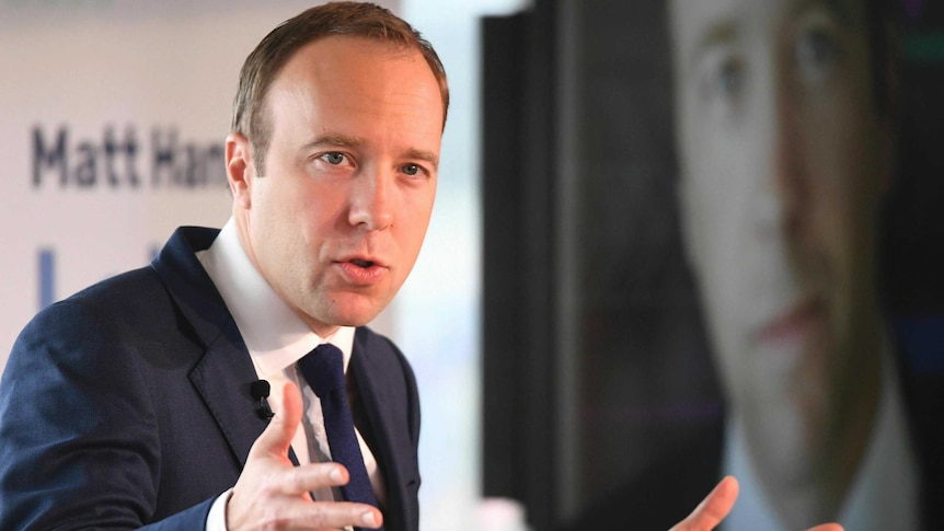 Britain's Health Secretary Matt Hancock talks animatedly as he stands in front of his campaign signs