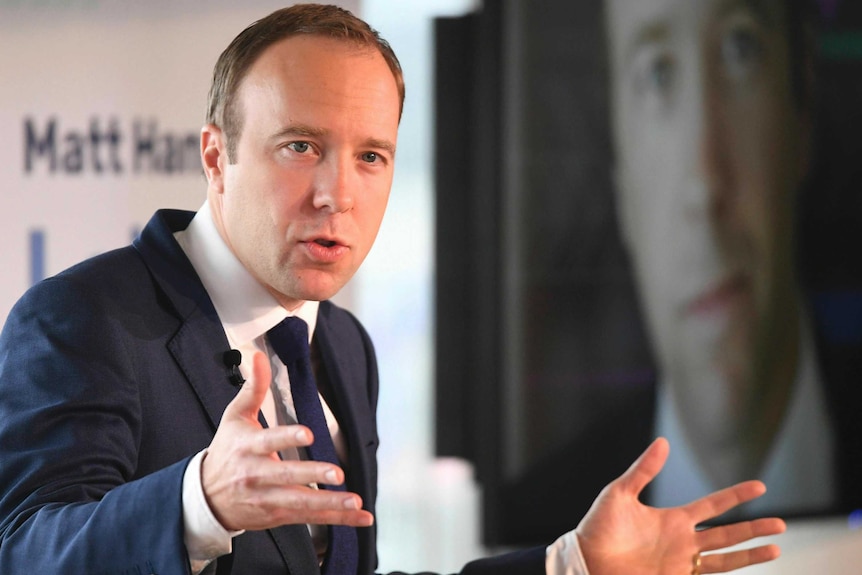 Britain's Health Secretary Matt Hancock talks animatedly as he stands in front of his campaign signs