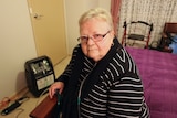 Eileen Kelly sits on a bed and has a tube in nostrils which is attached to medical equipment used to treat pulmonary fibrosis