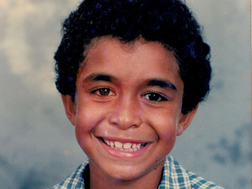 A photo of young Daniel Love, smiling and wearing a checked shirt.