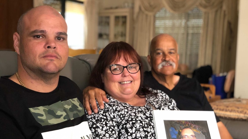 Paul Caliste (left), with mother Michelle holding a photo of her son Robbie, and father John Caliste sitting on a sofa.