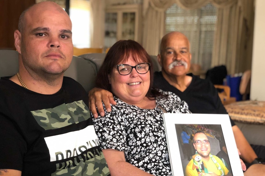 Paul Caliste (left), with mother Michelle holding a photo of her son Robbie, and father John Caliste sitting on a sofa.