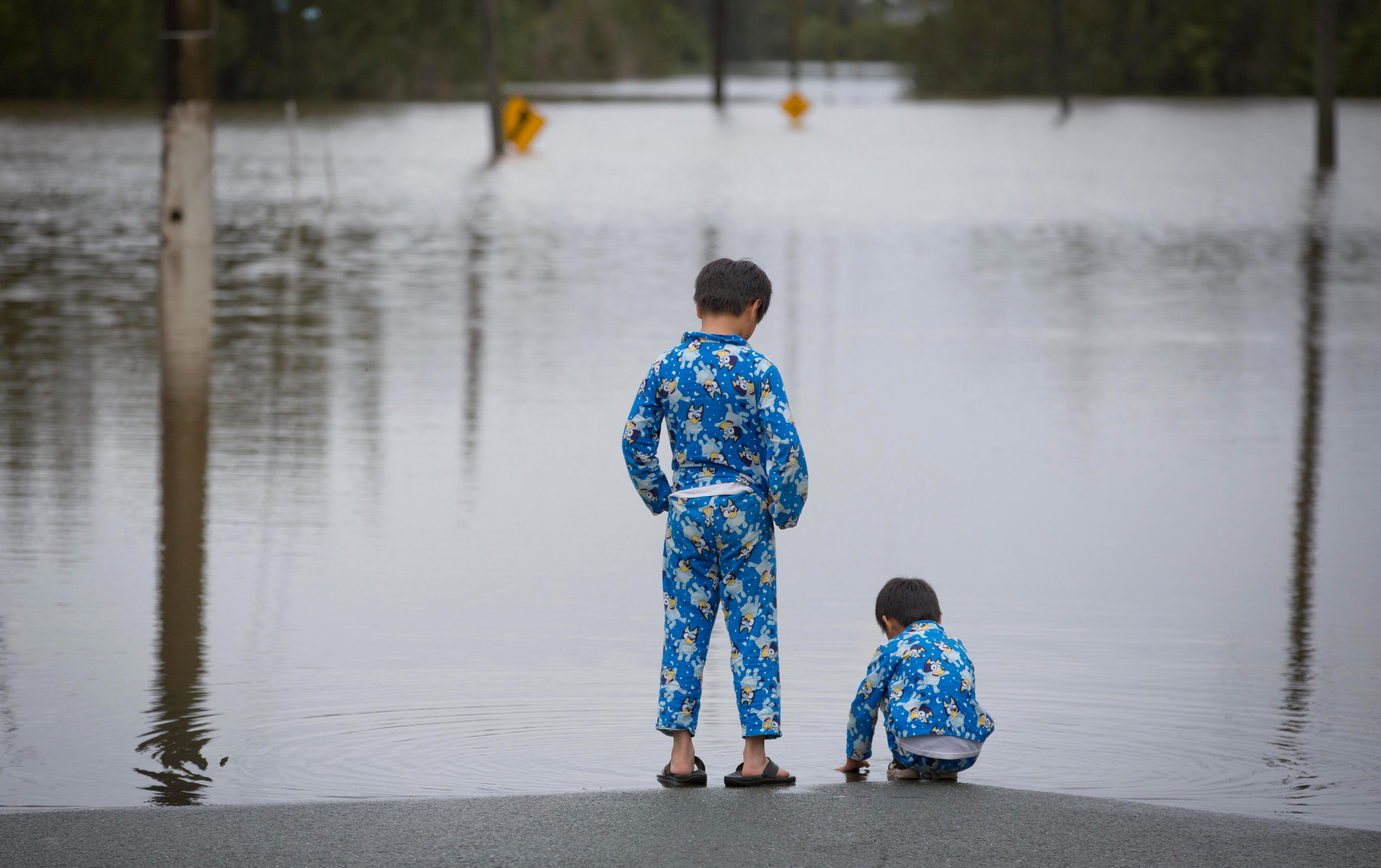 Kids in Bluey pjs examine a flooded road, road signs in the background