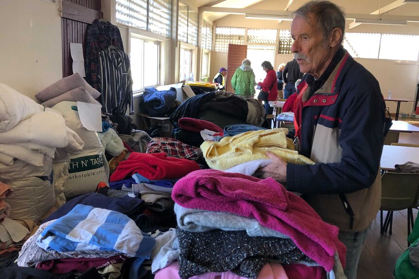 A man stacks donated clothes on a table.