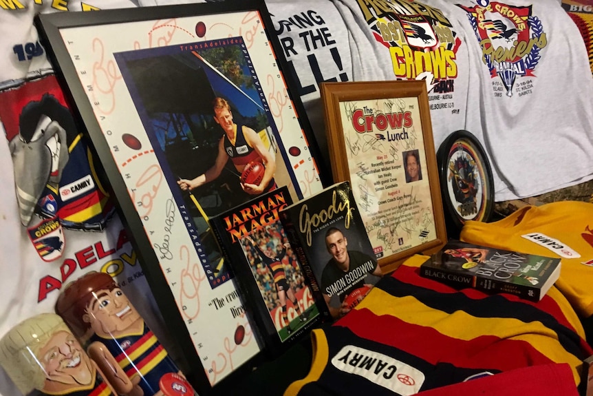 A collection of Adelaide Crows t-shirts, frames and books lined up