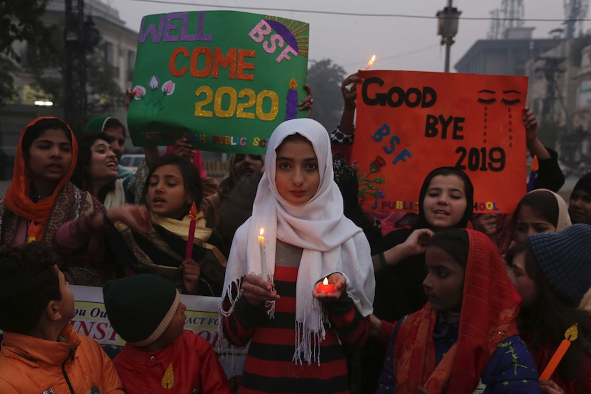 Pakistani children hold candles and New Year signs during a candlelight vigil.