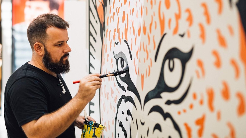 Currumbin street artist Kiel Tillman painting a leopard, as part of the Detour Street Art Festival on the Gold Coast.