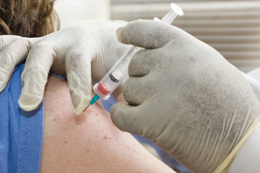 A person is getting the flu jab in their shoulder