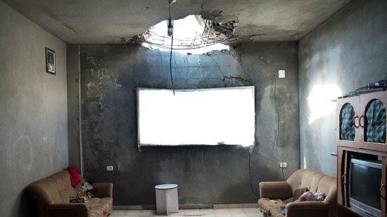 A lounge room with a huge hole in the ceiling.