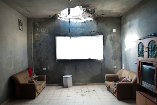 A lounge room with a huge hole in the ceiling.