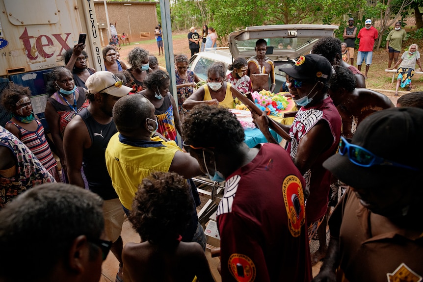 A crowd of people standing around the coffin of late Australian actor David Gulpilil.