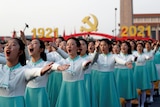 天安门中共建党百年仪式上，一群穿着蓝色裙子的女学生举起手臂。