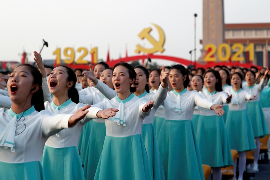 天安门中共建党百年仪式上，一群穿着蓝色裙子的女学生举起手臂。