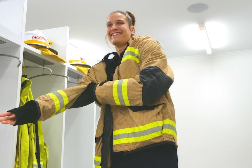 A fire officer pulls on her jacket.