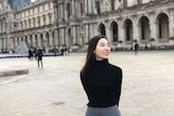 一名女性站在卢浮宫前