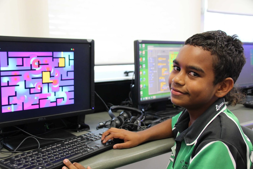 Smiling primary student Jahkiel sitting in front of his computer, displaying a game.