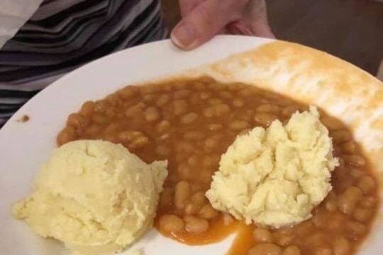 A plate of unappetising mashed potato and baked beans.