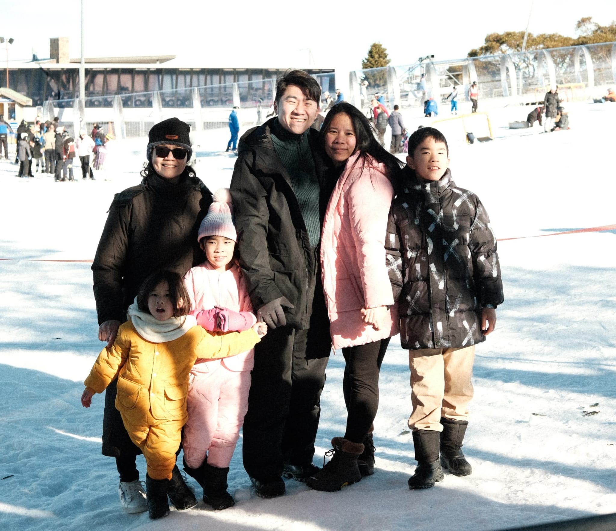 a family pose and smiling to the camera with snow in the background